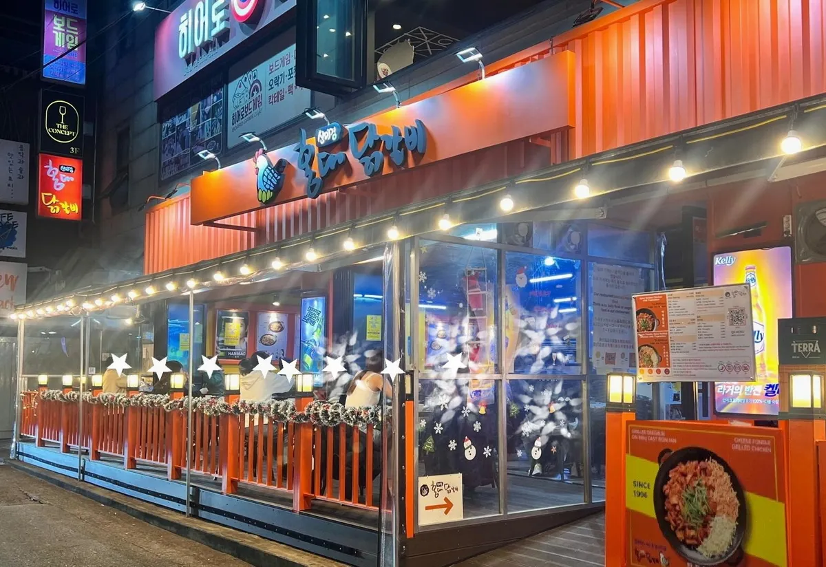 Shin Mi-kyung Hongdae Dakgalbi vibrant night view with orange signage and outdoor seating