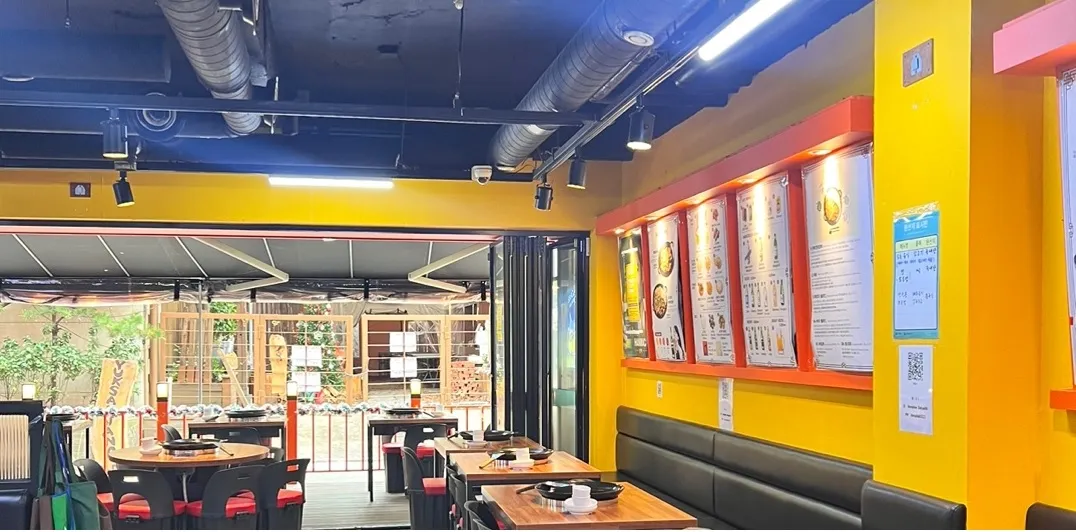 Modern interior dining area with yellow columns, menu boards, and spacious seating